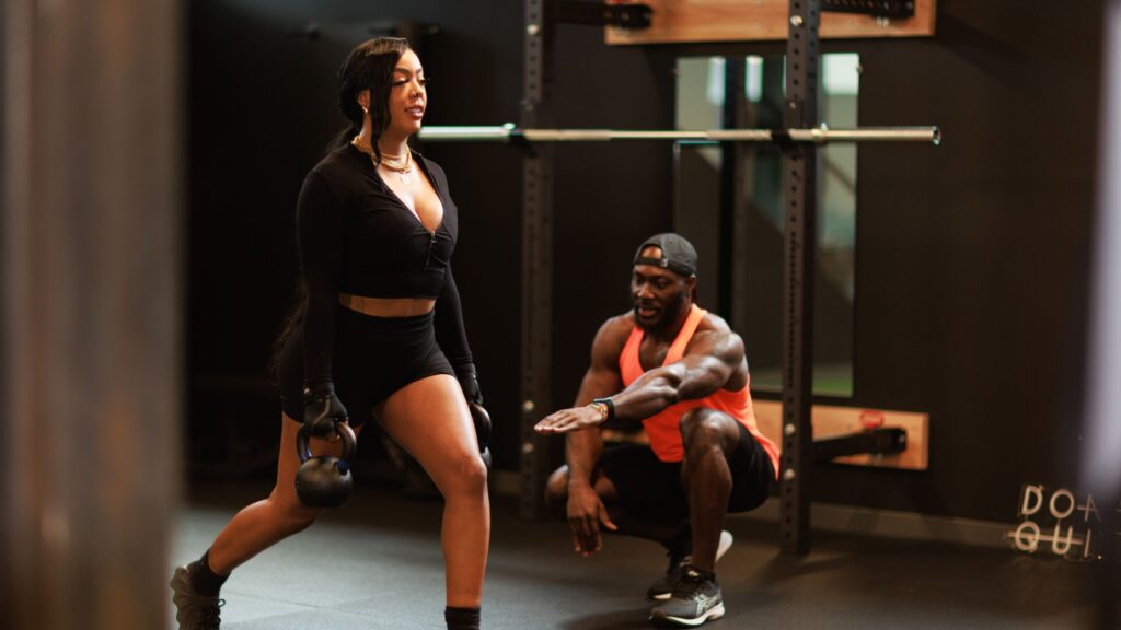 Denver personal trainer guiding a client through proper strength training form in a gym.
